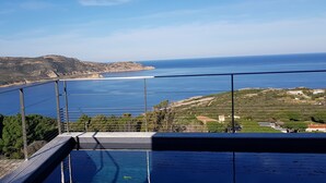 En pool med udsigt til havet og bakker.