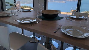 Et spisebord dækket til fire med udsigt til havet og bakker.