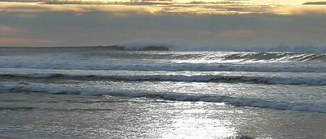 A beach with waves and a cloudy sky.