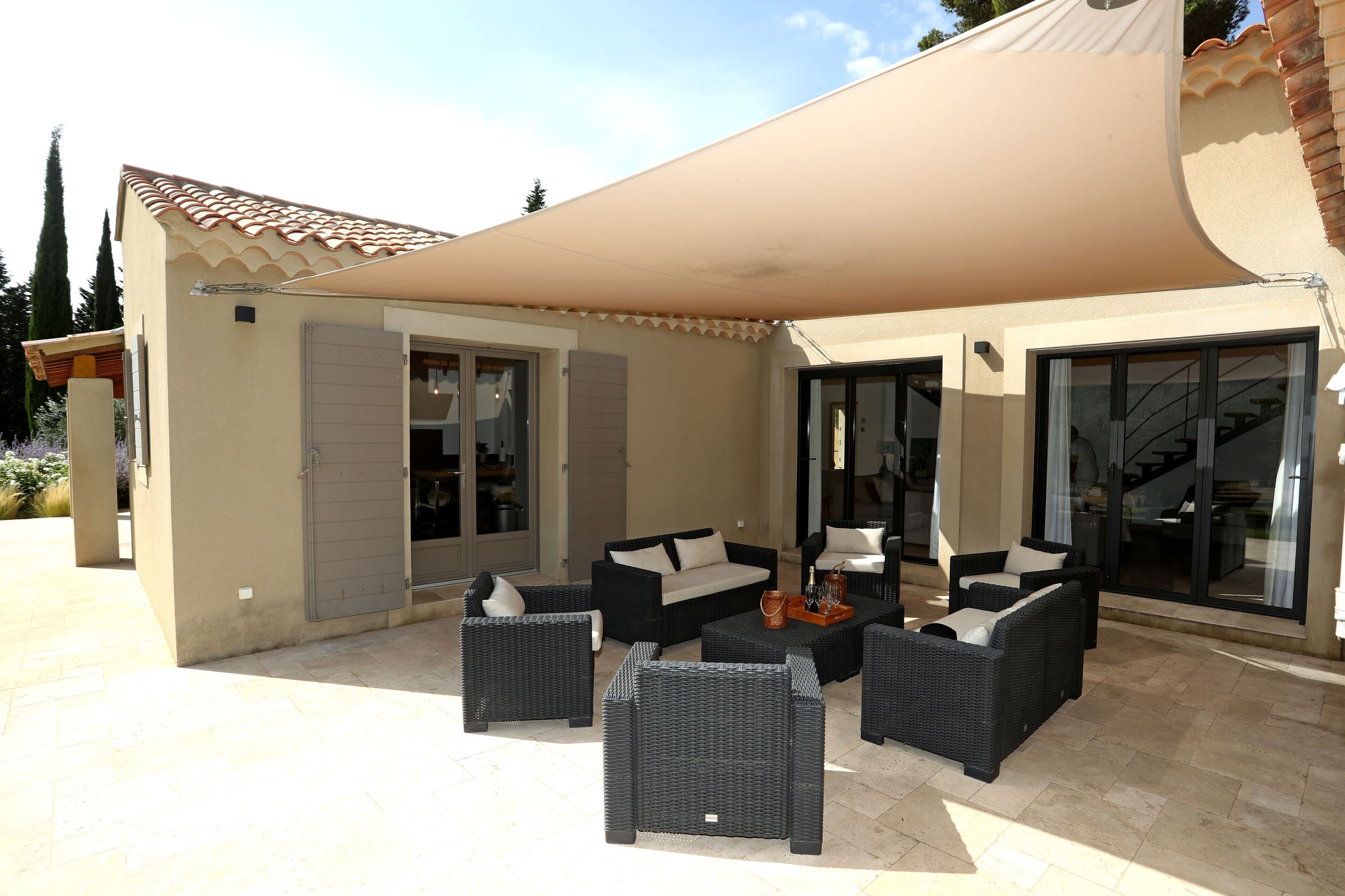 An outdoor patio with wicker furniture and a large umbrella.