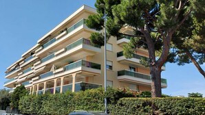 Un edificio residenziale a più piani con balconi, immerso nel verde e alberato.