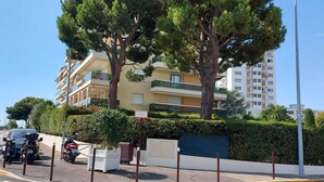 Zona residenziale con un edificio a più piani, motociclette parcheggiate e cielo sereno.