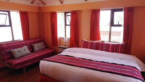 A room with a large bed, a sofa, and two windows with red curtains. - Casa de Valentin (Capachica)
