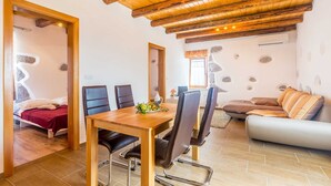 A cozy room with a wooden ceiling, a dining table with chairs, a sofa, and a bed with a red blanket. - Beautiful holiday house KORNIC (Kornić)