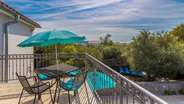 A balcony with a table and chairs, a green umbrella, and a view of the surrounding landscape. - Beautiful holiday house KORNIC (Kornić)