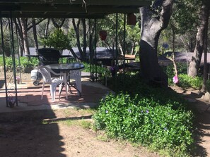 Relax under the shade of a pergola, surrounded by lush greenery and trees.