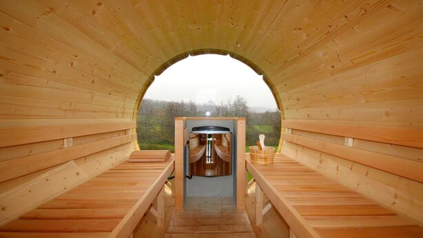 Uma sauna de madeira com bancos de cada lado e um espaço para sauna no centro.