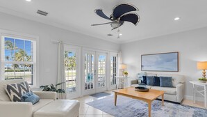 Un salón amplio con un sofá blanco, una mesa de centro y un ventilador de techo.