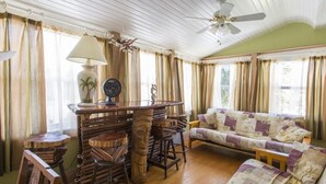 Une pièce chaleureuse avec un bar en bois, un canapé et un ventilateur de plafond.