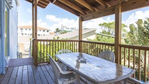 Une terrasse en bois avec une table et des chaises, donnant sur un quartier résidentiel avec des maisons et de la verdure.