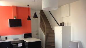 Eine moderne Küche mit Schwarz-Weiß-Farbgebung, einer Holztreppe und einem hellen Essbereich.