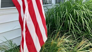 Ein Gebäude mit einer großen amerikanischen Flagge davor, einem Kompass-Symbol an der Wand und der Zahl '223' im Fenster.
