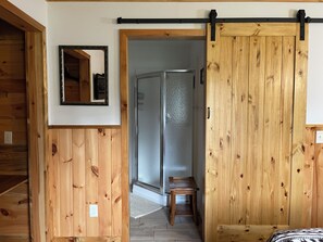 Un interior de madera con una puerta corredera, un espejo y una pequeña mesa de madera.