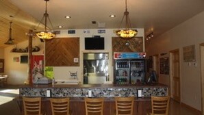 A bar area with a counter and bar stools, a television mounted on the wall, and a refrigerator.