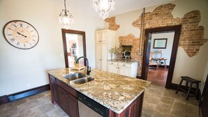 A kitchen with a granite countertop, stainless steel sink, and a dishwasher. There is a brick wall and a wooden cabinet. - Historic Home, Modern & Charming Decor, Wine Trail, Private Rental (Alto Pass)