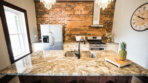 A kitchen with a granite countertop, stainless steel sink, and a brick backsplash. - Historic Home, Modern & Charming Decor, Wine Trail, Private Rental (Alto Pass)
