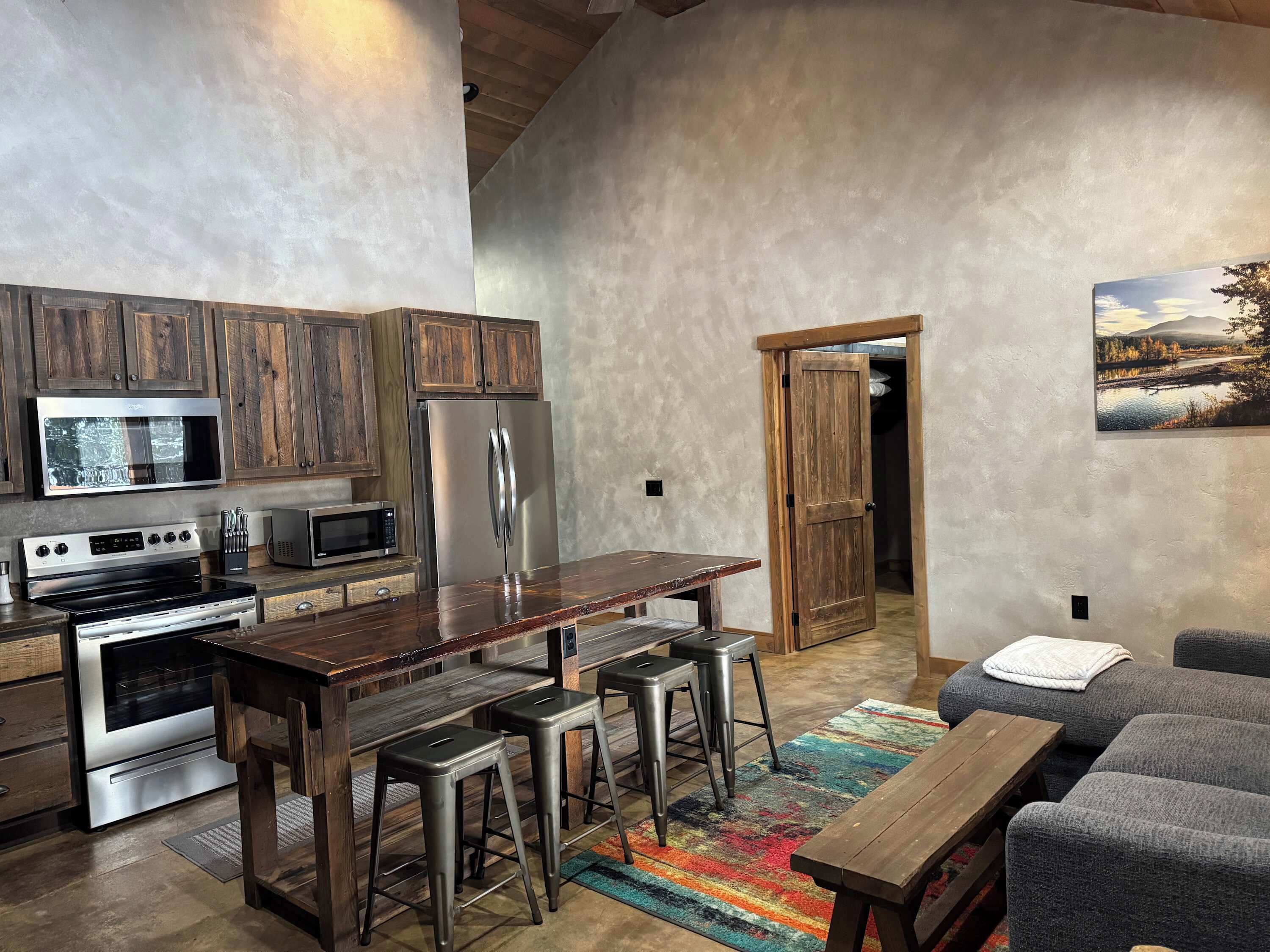A modern kitchen with wooden cabinets, stainless steel appliances, and a bar area with stools.