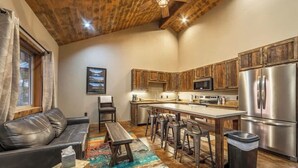 A modern kitchen with wooden cabinets, stainless steel appliances, and a bar area with stools. - GNP Explorers Stay Here–2bd/1ba K/Q Bed-7mi To GNP (Coram)