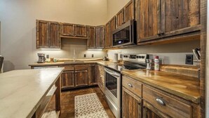 A kitchen with wooden cabinets, a microwave, an oven, and a coffee maker. - GNP Explorers Stay Here–2bd/1ba K/Q Bed-7mi To GNP (Coram)