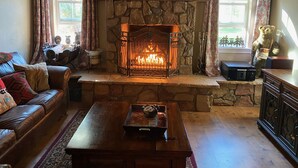 A cozy living room with a stone fireplace, leather sofa, and a coffee table. - Riverfront Retreat. Year-round river in North Payson. (Payson)