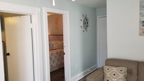A hallway with a door leading to a bedroom with a bed and a decorative wall piece. - A Stone Throw to Beach and Convention Center and Two Blocks from the Crest!! (Wildwood)