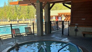 Uma área de piscina coberta ao ar livre com um deck de madeira, pilares de pedra e um aviso sobre mergulhos.