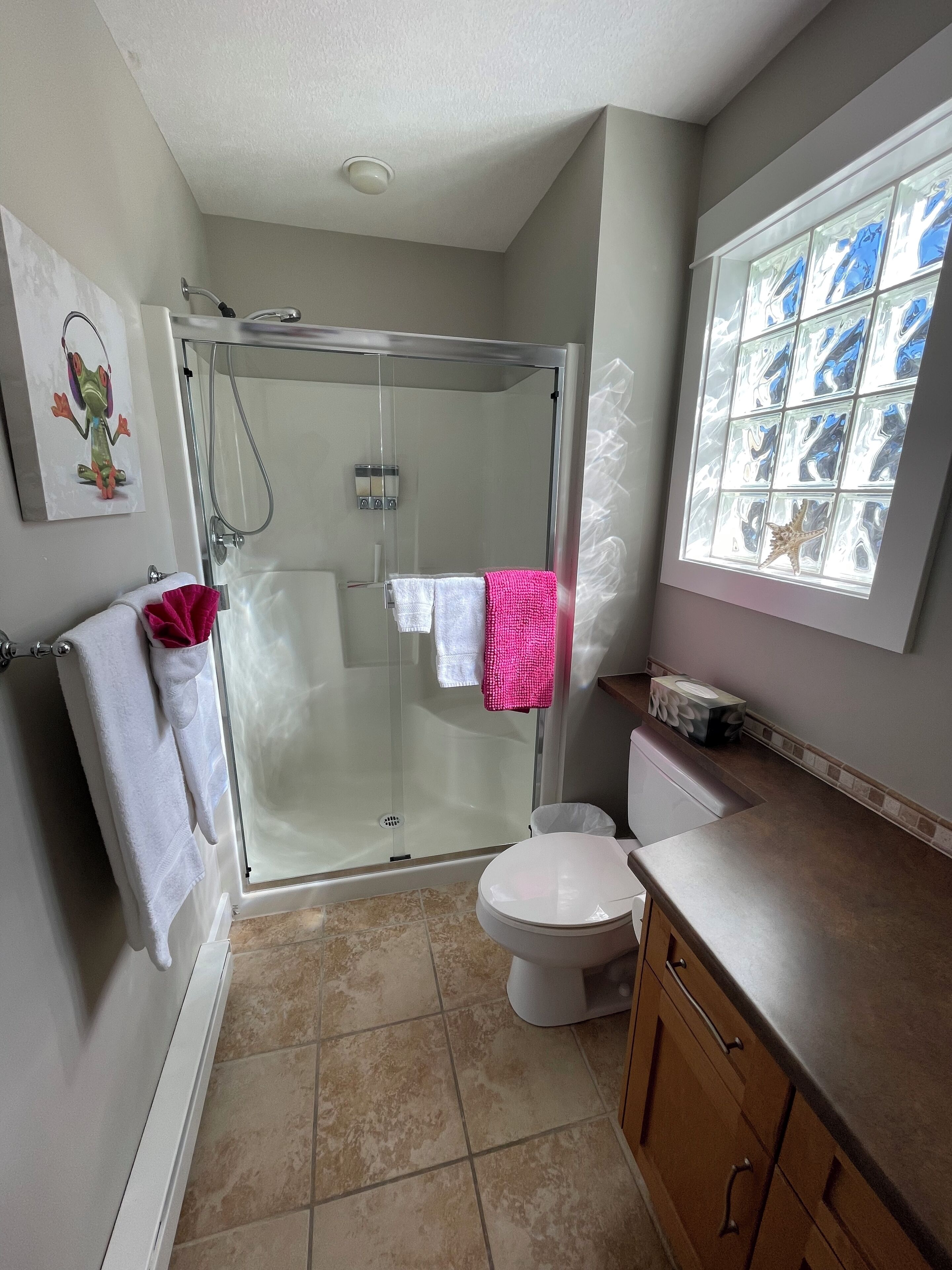 Un baño moderno con cabina de ducha de vidrio, inodoro y lavamanos.