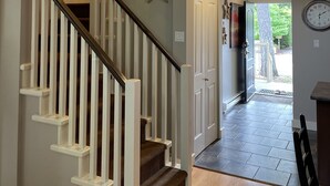 A multi-level interior with a staircase, a door leading outside, and a clock on the wall. - Starfish Cottage - Oceanside Village Resort (Parksville)