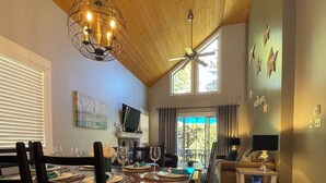 A dining area with a wooden ceiling, a chandelier, and a view of the outdoors. - Starfish Cottage - Oceanside Village Resort (Parksville)