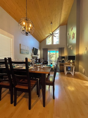 Enjoy meals in this dining area with a large table for six, a chandelier, and a television.