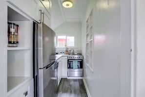 A narrow kitchen with a refrigerator, oven, and sink.