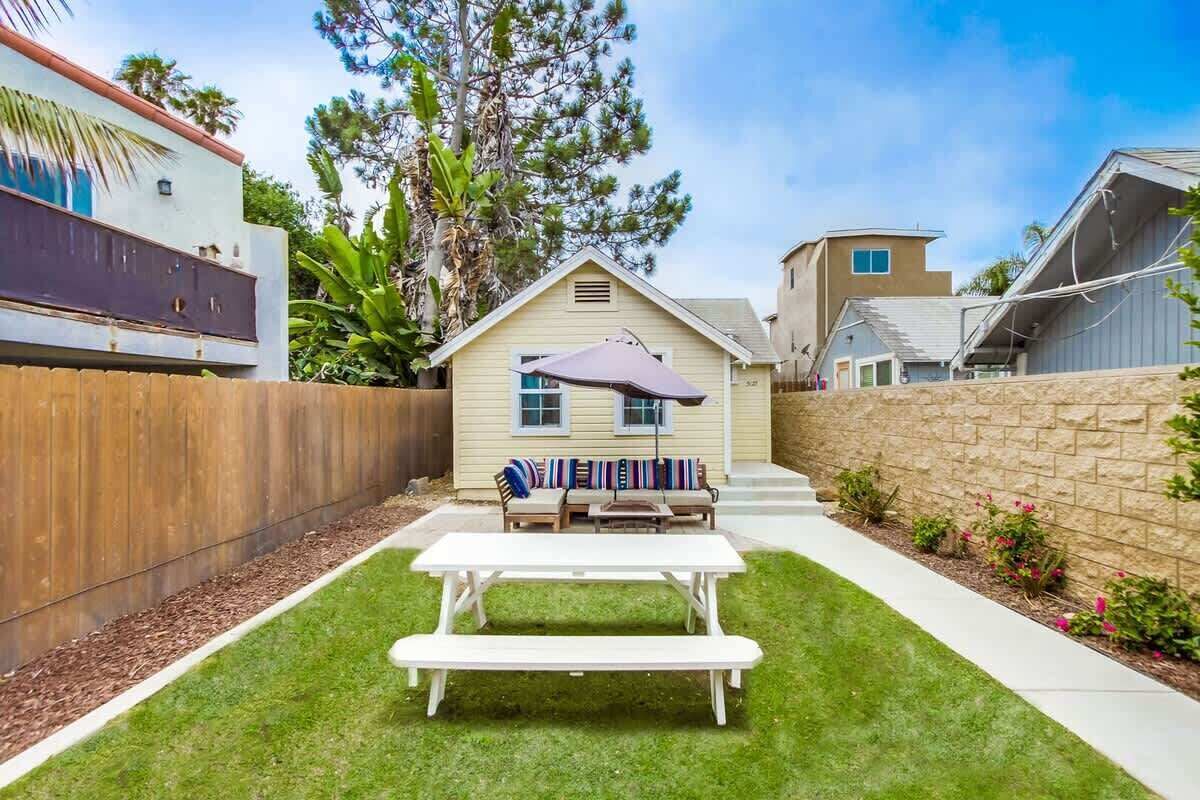 A backyard with a picnic table and a covered seating area.