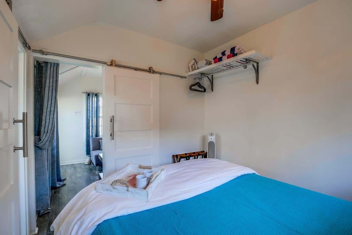 A bedroom with a bed, a door, a radiator, and a shelf with items.