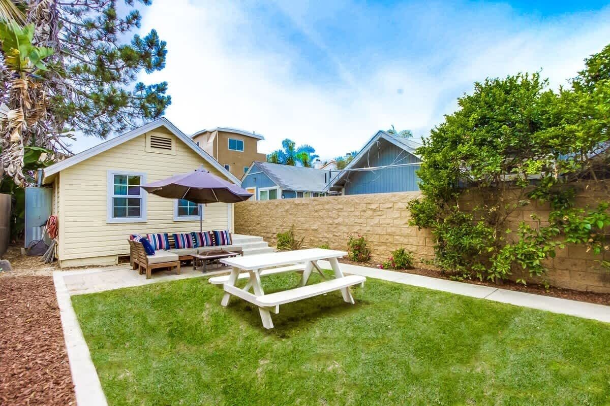 A backyard with a picnic table, a covered seating area, and a stone wall.