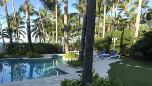A pool area with palm trees, lounge chairs, and a stone pathway. - Seaside Apartment (Las terrenas)