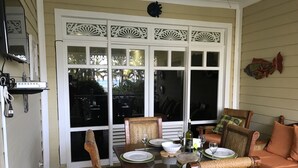 A dining area with a table set for four, surrounded by wicker chairs, and a sofa with cushions. - Seaside Apartment (Las terrenas)