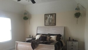 A bedroom with a wooden bed, two bedside tables, a nightstand, a window, and a painting on the wall. - right at home in Nashville (Nashville)