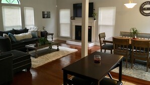 A living room with a sofa, coffee table, and dining table. There is a fireplace and a TV mounted on the wall. - right at home in Nashville (Nashville)