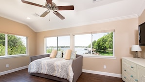 A bedroom with a bed, large windows, a ceiling fan, and a dresser. - A lakefront getaway (Willis)