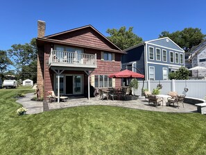 A two-story house with a balcony, a patio with outdoor furniture, and a well-maintained lawn.