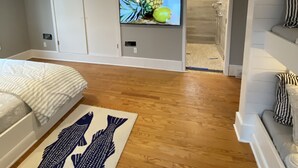 Un dormitorio con una cama, televisión, piso de madera y armario.