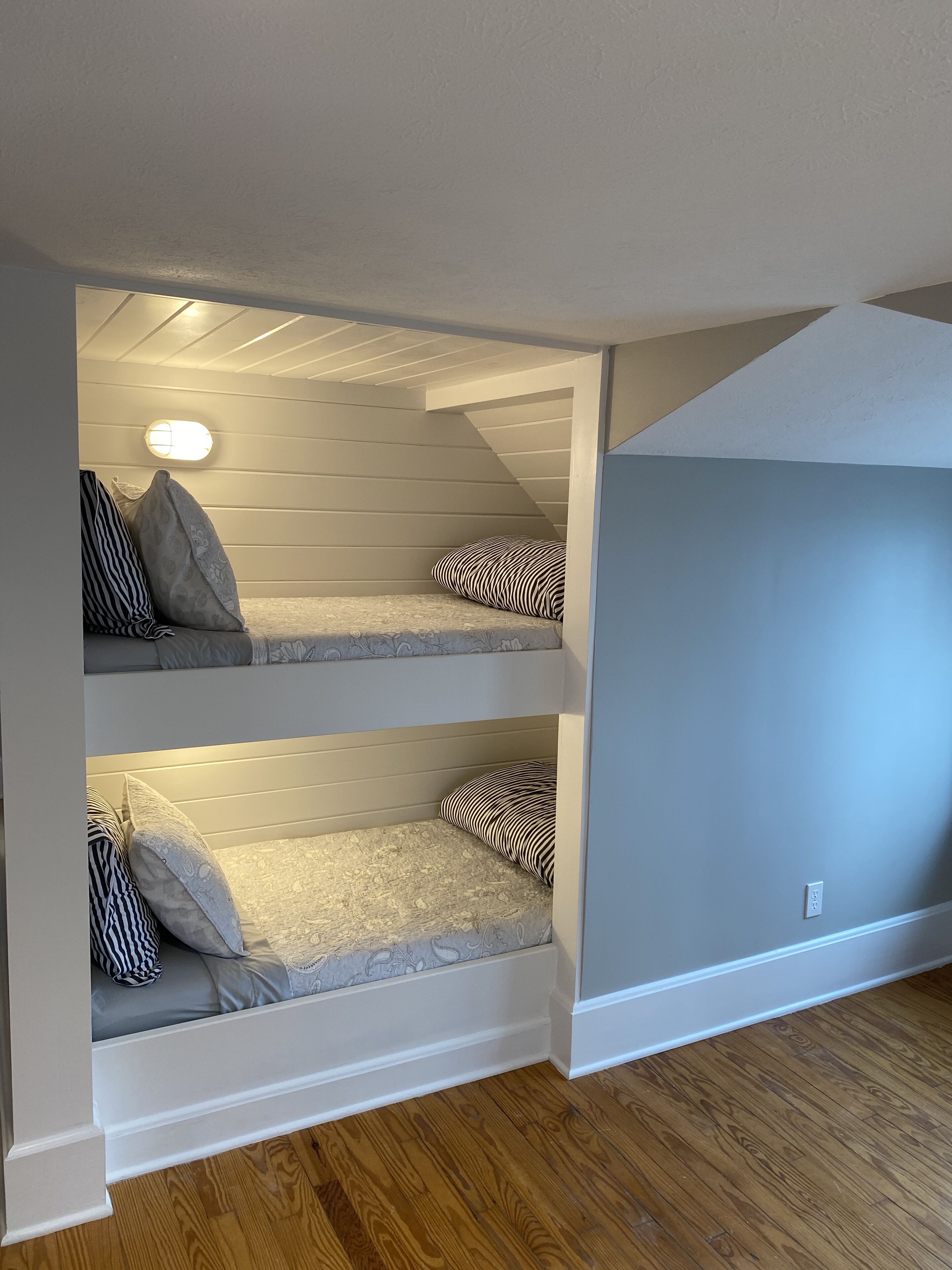 Une chambre avec deux lits superposés, un plancher en bois et un plafond en pente.
