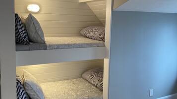 Une chambre avec deux lits superposés, un plancher en bois et un plafond en pente.