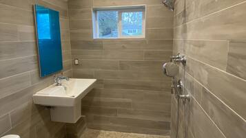 Une salle de bain avec douche, toilettes et lavabo.