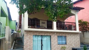 A two-story house with a balcony, a staircase, and a small garden area.