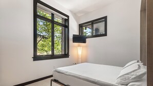Una camera da letto con un letto, una finestra, una TV a parete e una lampada da comodino.