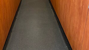 A hallway with wooden lockers and a black floor.