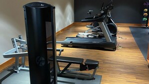 Una palestra con attrezzature per esercizi, tra cui una macchina per pesi, tapis roulant e una panca.