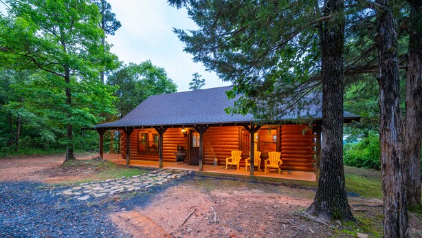 A log cabin with a porch, stone pathway, and chairs. - Mountain Vista Retreat-Issi is secluded, with sunset views of the Kiamichi Mnts. (Smithville)