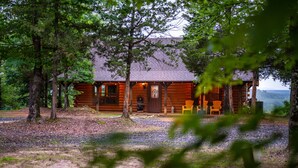 A rustic log cabin with a porch, surrounded by trees and a gravel path. - Mountain Vista Retreat-Issi is secluded, with sunset views of the Kiamichi Mnts. (Smithville)
